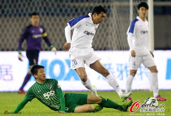  Shanghai Shenhua's Xu Liang tackled by defender.