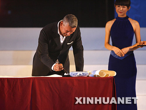 8月30日，巴乔（左）在新闻发布会上用毛笔写字。当日，意大利著名球星罗伯特·巴乔出席了在北京举行的新闻发布会。巴乔此次访华的目的是来担任“历届奥运会会徽、吉祥物”纪念章宣传大使。 新华社记者郭勇摄 