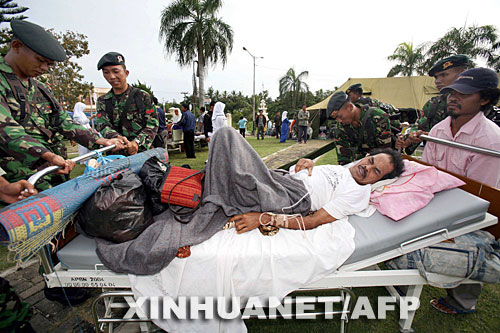 9月13日，在印度尼西亚明古鲁的一家医院外，参加救援的士兵帮助一名受伤的男子。新华社/法新