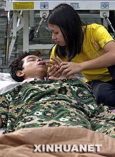 9月13日，在印度尼西亚的明古鲁省一家医院外面搭建的临时屋棚里，医护人员为一名受伤的男子治疗。新华社/法新