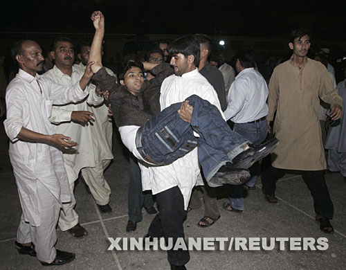 10月19日，在巴基斯坦南部港口城市卡拉奇，醫護人員運送一名在爆炸中受傷的男子。據巴基斯坦電視臺19日報道，當天淩晨在卡拉奇，剛剛回國的前總理貝·布托所乘坐的車輛附近發生自殺式爆炸襲擊，已造成124人死亡，近400人受傷，貝·布托本人安然無恙。