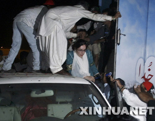 10月19日，在巴基斯坦卡拉奇，巴前總理貝·布托（中）在爆炸發生後轉移到防彈車。據巴基斯坦電視臺報道，當天淩晨在南部港口城市卡拉奇，剛剛回國的前總理貝·布托所乘坐的車輛附近發生自殺式爆炸襲擊，已造成124人死亡，近400人受傷，貝·布托本人安然無恙。