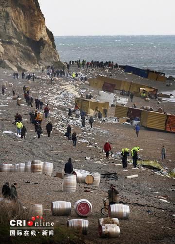 2007年1月22日，英国德文郡的布兰斯科姆海滩，人们从搁浅的那波利号货船上取出货物。1月18日，那波利号遭遇风暴搁浅，目前船身已经倾斜，船尾沉在水中，数十个集装箱落水，其中有一些装有有毒有害物质的集装箱发生泄漏。