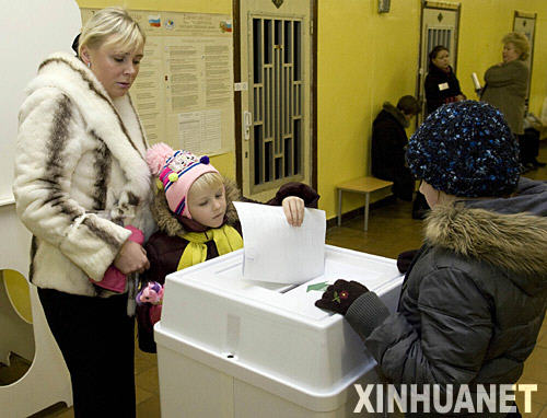 12月2日，一名妇女带着孩子在俄罗斯首都莫斯科的一个投票站投票。