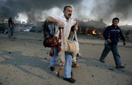 2007年2月18日，巴格達東南部一個市場內，一名伊拉克男子懷抱一個在汽車炸彈爆炸事件中死去孩子的屍體。