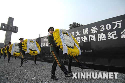 12月13日，武警戰(zhàn)士在敬獻花圈。     當日上午10時，凄厲的警報聲響徹南京城上空。中央和國家有關部門、江蘇省暨南京市各界代表，以及海內外和平友好人士近8000人，在侵華日軍南京大屠殺遇難同胞紀念館集會廣場，隆重舉行悼念侵華日軍南京大屠殺30萬同胞遇難70周年暨侵華日軍南京大屠殺遇難同胞紀念館擴建工程竣工儀式。 新華社記者 韓瑜慶 攝 