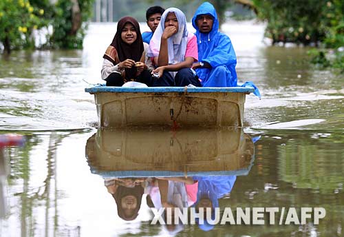 12月17日，在泰国的那拉提瓦府，当地村民在洪水中乘小船出行。 近日，泰国南部地区遭遇洪灾，部分地区灾情严重。 新华社/法新