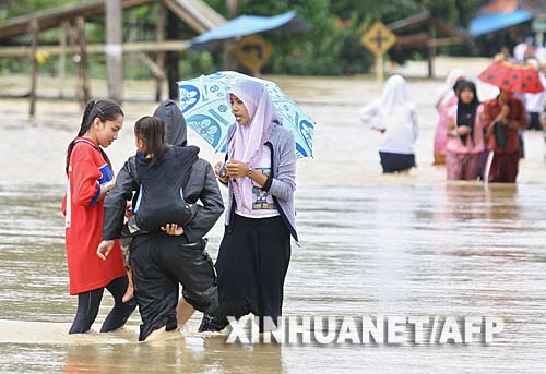 12月17日，在泰国的那拉提瓦府，当地村民趟着洪水出行。新华社/法新