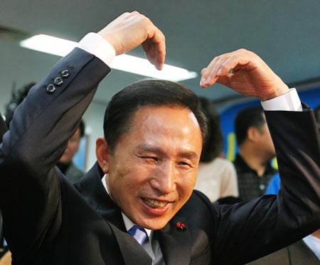 12月19日，李明博在首尔大国家党总部的电视会议上用手做出一个心形图案。