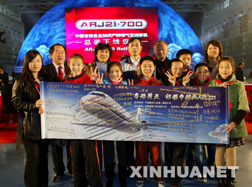 上海市政立路二小少先队员代表为ARJ21总装下线带来了他们专门创作的“寄语蓝天——红领巾献礼ARJ21”油画，并附上全班24名同学对ARJ21的美好祝愿，中航商用飞机有限公司总经理罗荣怀（后排居中者）与少先队员代表合影。新华社记者 伍靖丹 摄