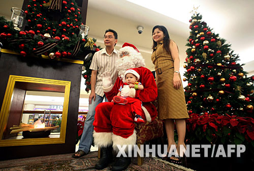 12月23日，在印度尼西亞首都雅加達的一個商城，“聖誕老人”與一個年輕的家庭一起合影。隨著耶誕節的臨近，“聖誕老人”的身影出現在世界各地，他們的各種表演為當地增添濃濃的節日氣氛。 新華社/法新 