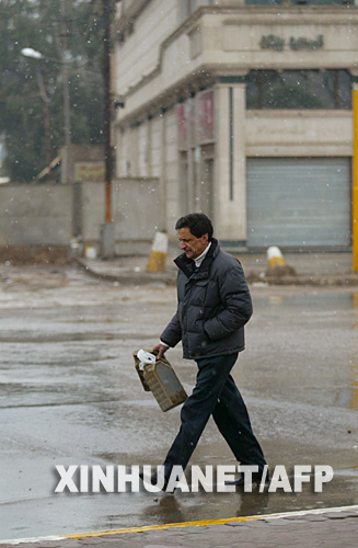 1月11日，一名男子冒雪走在伊拉克首都巴格达街头。