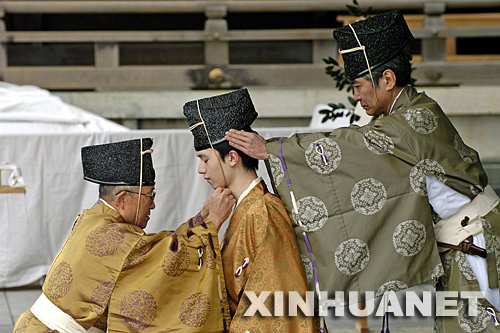 1月14日，在日本首都东京明治神宫举行的“成人节”庆祝活动上，两名神官为一名年满20岁的年轻人行“冠礼”，祝贺其成年。