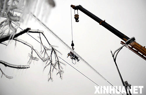 2月2日，一名电力工程人员在湖南郴州王仙岭用木棒清除电线上的积冰。