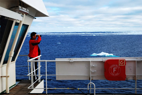 “雪龙”号极地科学考察船船长沈权在船上进行观察。