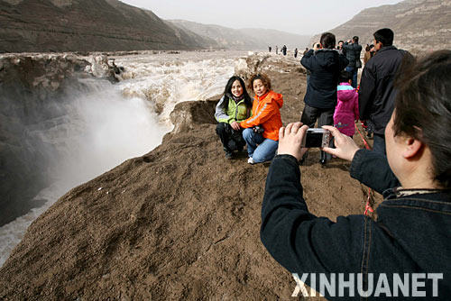 3月1日，游客在黄河壶口瀑布前拍照留念。