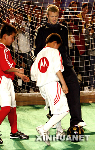  3月3日，美国洛杉矶银河队球员贝克汉姆（上）在辅导上海民工子弟学校的学生踢足球。