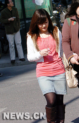 3月4日，一名身着春装的女青年行走在北京西单商业街。