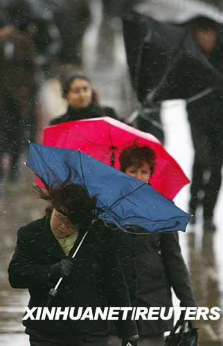 3月10日，在英國倫敦塔橋上，行人頂著風(fēng)雨行走。