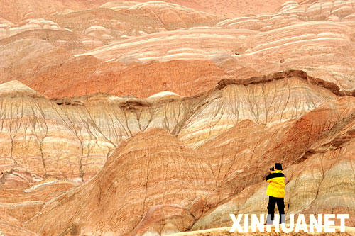 3月12日，一名游客在临泽丹霞地貌景区内拍照。