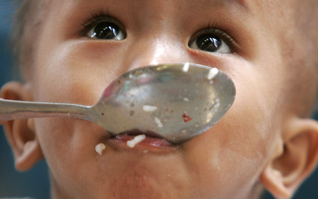 4月7日，菲律賓首都馬尼拉貧民區的一名兒童在吃飯，菲是世界最大的稻米進口國。