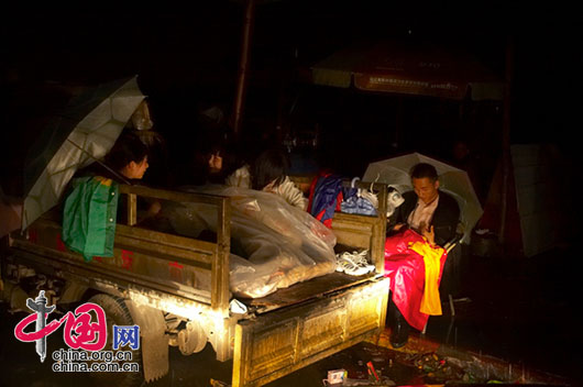 5月13日夜，四川省都江堰市灾区，路边以小货车作临时帐篷的一户人家。五位女人挤在一个货车厢里取暖，男人只好坐在椅子上过夜。