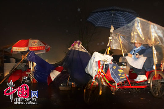 5月13日夜，四川省都江堰市灾区，一对老伴以自己的三轮车作临时帐篷，老大妈央求我给她找一个塑料袋遮雨。