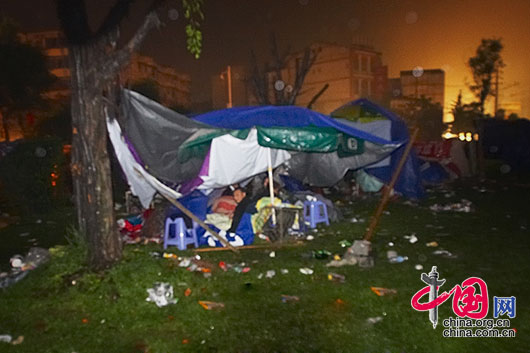 5月13日夜，四川省都江堰市灾区，一些灾民在积水的草坪搭起简陋的帐篷。 李肖军/摄影