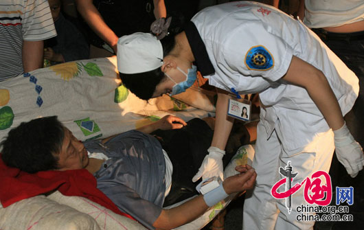 5月12日夜，四川都江堰市聚源镇中学，一名护士察看伤者的病情。