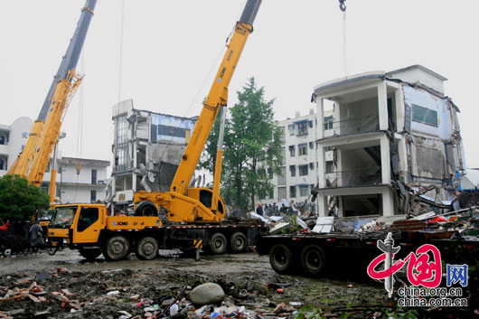 5月13日上午，四川都江堰市聚源镇中学，工程车辆在震后废墟上。