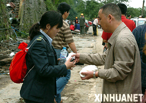 5月14日，志愿者（右）在为从灾区走出的人分发食物