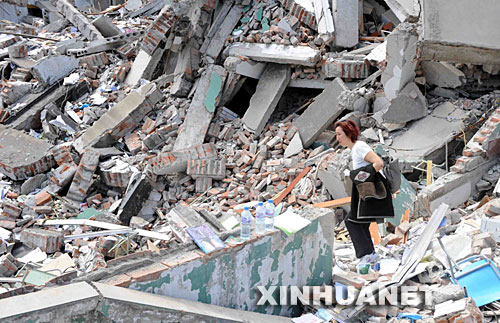 　　5月14日，一位妇女在四川北川县中学的废墟里呼唤寻找被埋在废墟里的亲属。受汶川地震影响，四川北川中学的教学楼倒塌，众多师生被埋在倒塌的校舍中。 新华社记者 李晓果 摄