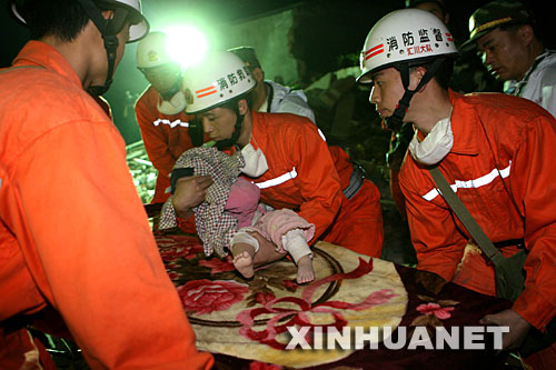 　　5月14日晚，消防抢险队员在四川绵竹市汉旺镇将1岁女孩沈天奇从废墟中成功救出。 新华社记者 李明放 摄