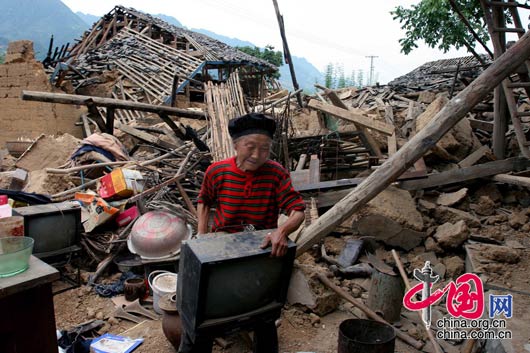 5月15日下午，甘肃陇南碧口镇，一名老妇人抢救家中的电视机。 田蹊/摄影