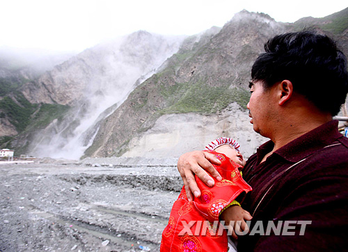 5月16日，四川理县一位灾民怀抱小孩观看强烈余震引起的山体滑坡