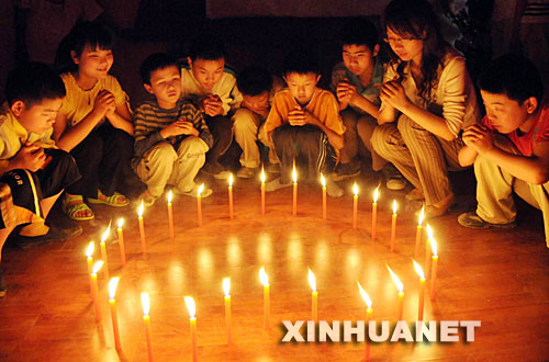 5月16日晚，湖北省宜昌市特殊教育学校的盲童们和校长（右二）一起围在点燃的蜡烛旁，为在地震中遇难的小朋友哀悼，为幸存者祈福。 新华社发(刘保平 摄) 
