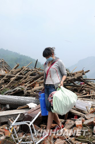 5月16日，四川省什邡市红白镇一位灾民在废墟上搜寻残留的生活用品