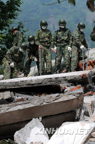 5月16日，解放军空降兵某师战士在四川什邡市红白镇初中的废墟中实施救援
