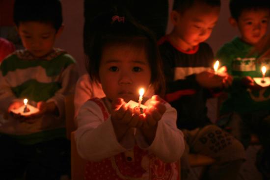 图文：幼儿园小朋友点起蜡烛进行祈祷