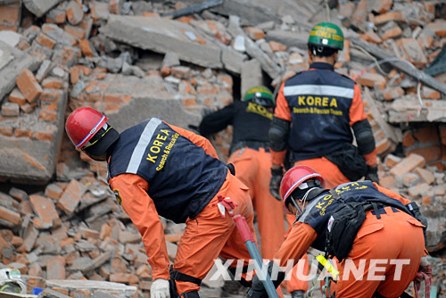 5月17日，韩国救援队的队员在废墟上搜寻幸存者。