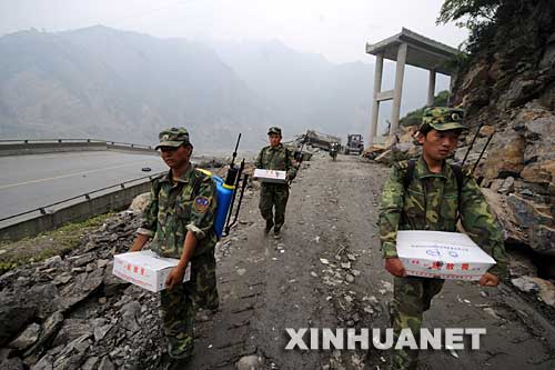 5月17日，因公路被余震阻断，搬运食品和药品的解放军战士步行前往映秀镇。