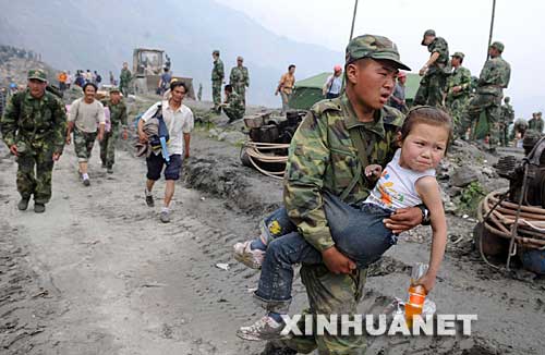 5月17日，一位解放军战士将一个小女孩抱着转移出映秀镇。
