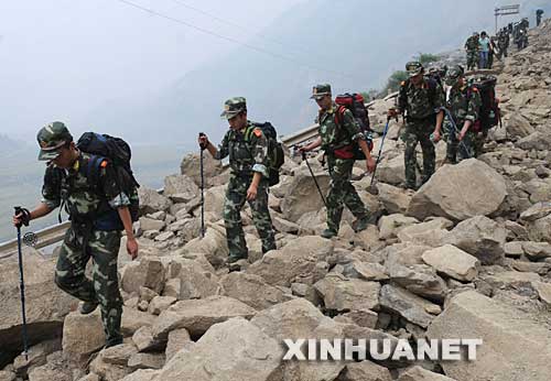 5月17日，因公路被余震阻断，一队解放军战士背着食品和药品步行前往映秀镇。
