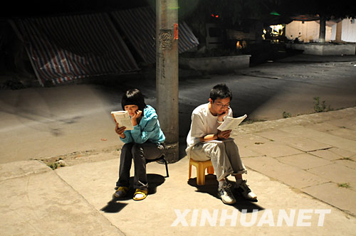 5月20日，什邡县城的两位高三学生在避震棚边的路灯下复习。 