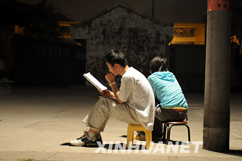 5月20日，什邡县城的两位高三学生在避震棚边的路灯下复习。 