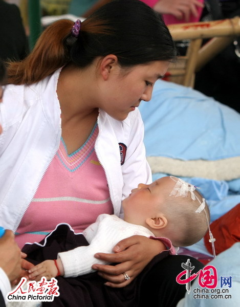 16日，绵竹妇幼保健院临时病房内，一位从重灾区汉旺赶来的年轻妈妈抱着伤后熟睡的婴儿。