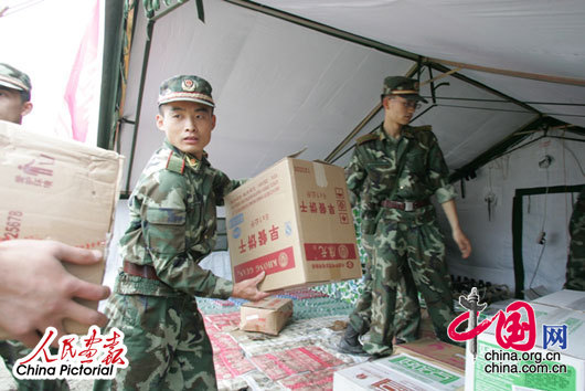 2008年5月14日下午，四川都江堰，在地震灾区进行抢险工作的武警官兵在搬运饼干、牛奶、饮用水等救援物资。