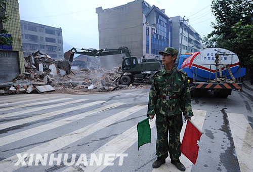 5月25日，一名解放军战士在清理地震废墟现场维持交通秩序。