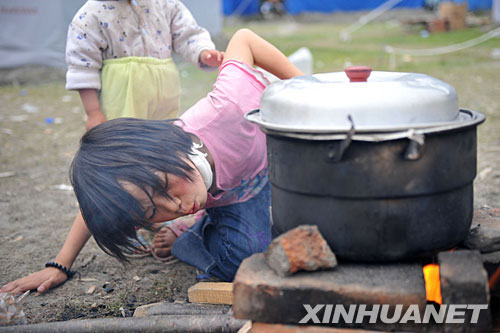 5月24日，10岁的王永霞在北川县地震灾区临时安置点内生火做饭。