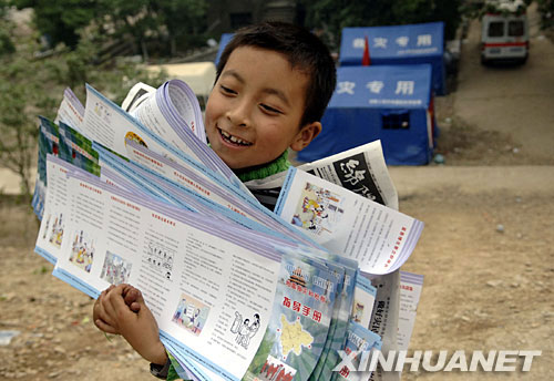 5月24日，中国科学院青年北川希望小学的小学生郝润林将防震知识手册搬回安置点。